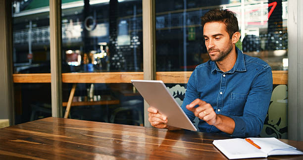 istock Cafe, man and reading on tablet for remote work, article information or online blog for publication. Coffee shop, male person and content writer with digital for freelancer, newsletter and editing 2224448175
