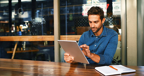 istock Remote work, man or typing with tablet at cafe for creative research, article submission and email. Freelancer, journalist and digital app at restaurant for proofreading story, blog review or editing 2224448184