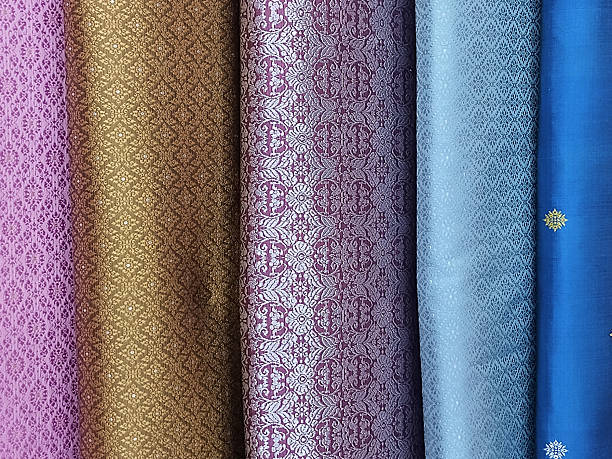 A stunning collection of exquisite silk cloth, meticulously crafted with detailed patterns, reflecting light beautifully across their diverse and rich hues.