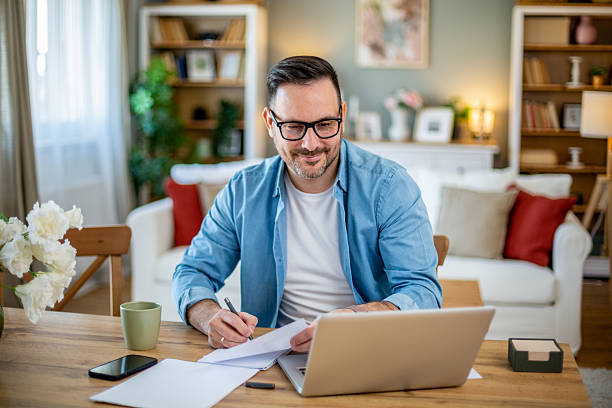 istock Mid adult man working from home, taking notes from his laptop 2224451950