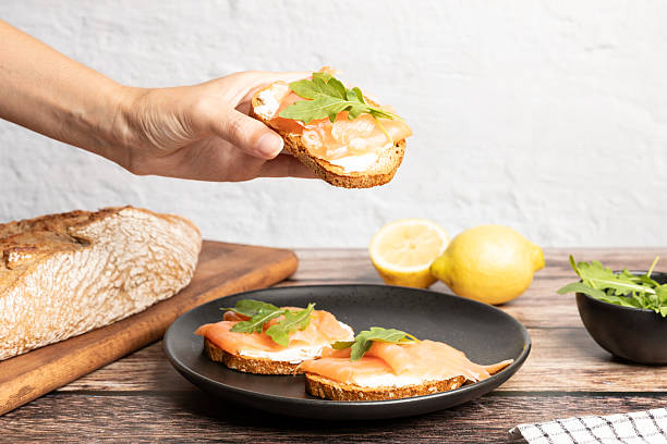 istock Hand holding smoked salmon toast served with arugula, healthy breakfast 2224452013