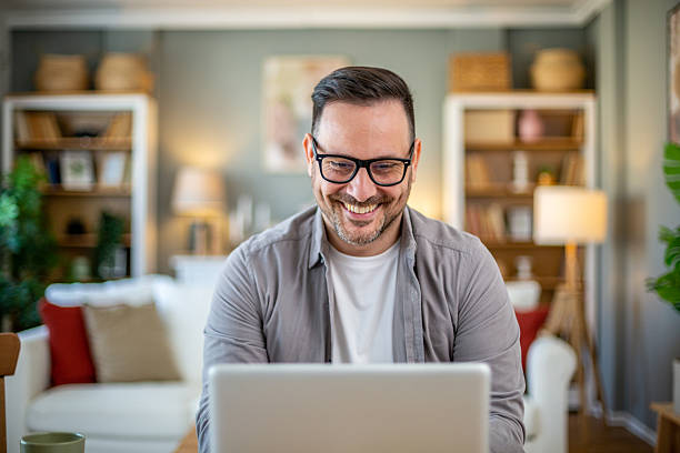 istock Smiling man working from home on laptop and enjoying it 2224452961