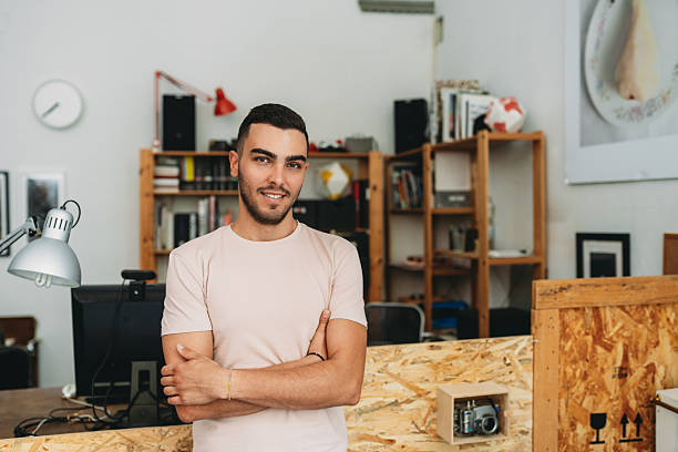 istock Young creative man smiling with arms crossed in his office 2224453170