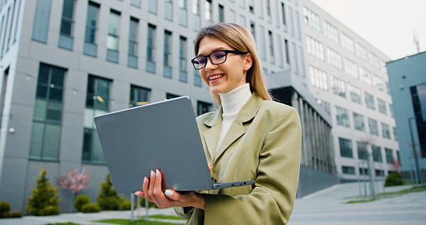 istock Smiling caucasian businesswoman or student university working or studying online using laptop on street. Remote work or learning concept 2224464195