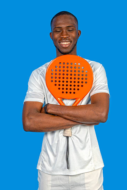 istock Paddle tennis player holding racket and smiling on blue background 2224464334