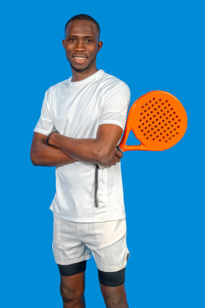 istock Confident padel player posing with crossed arms and paddle on blue background 2224464495