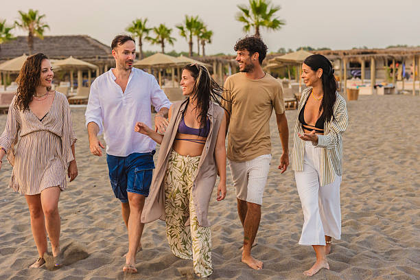 istock Friends walking and talking on beach at sunset 2224464571