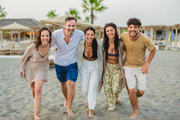 istock Five happy friends walking on the beach at sunset 2224465106