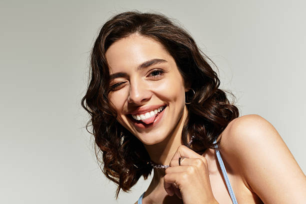 istock Young woman poses playfully in studio with flawless makeup and charming expression 2224466322