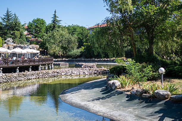 Beautifully landscaped garden with manicured trees and a lush green lawn: A charming holiday resort in Istanbul's Tuzla district. The artificial water channel offers a stunning view among the trees. Tuzla Istanbul, Turkey: July 15, 2023.