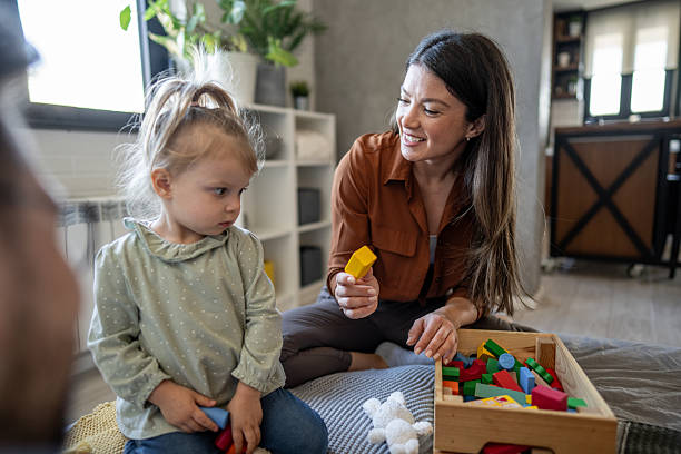 istock Babysitter playing with child at home using building blocks 2224476494