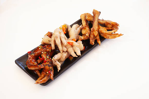 Chicken feet on a black plate. they are cooked in three different ways. some are fried, some are boiled in soup and some are covered with a sticky sweet barbeque.