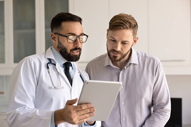 istock Serious medical practitioner man and patient looking at medical report 2224480426