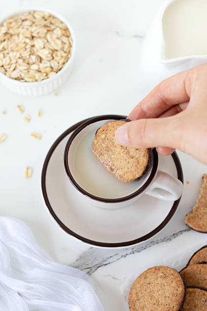 Hand is dipping breakfast cookie in a cup of oat milk