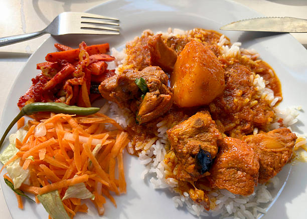 Mutton Curry and Rice served on a plate with carrot garnish
