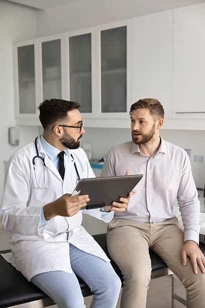 istock Serious Latin general practitioner man asking male patient about complaints 2224483612