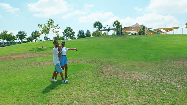 Family strolls through a sunny park, enjoying quality time together on a lush green hillside