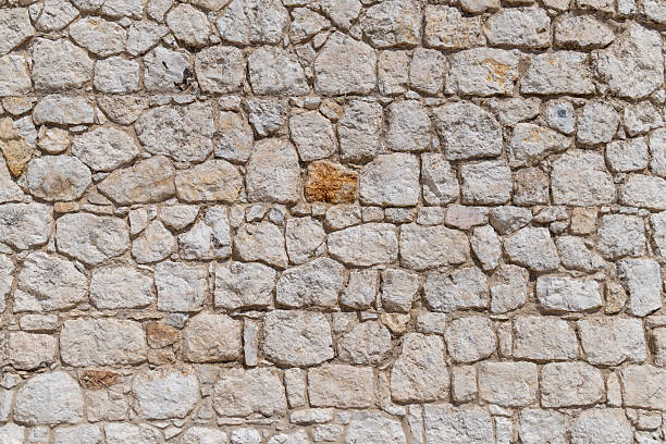 istock Close-up of rustic stone wall with uneven texture in sunlight 2224485430