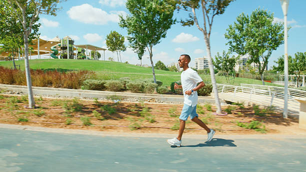 istock Young man jogging in urban park on sunny day 2224485461