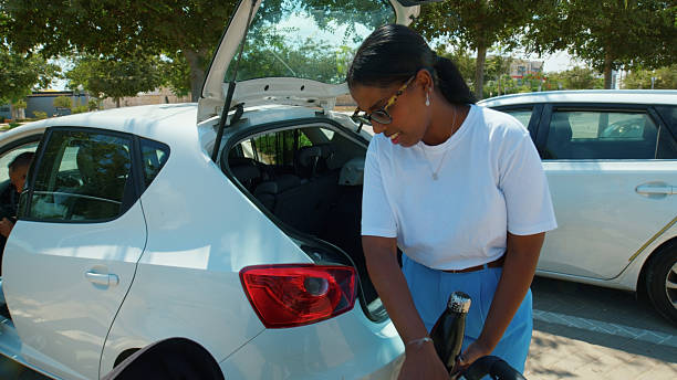 Mother loading luggage into car trunk while child waiting inside, ready for a family trip