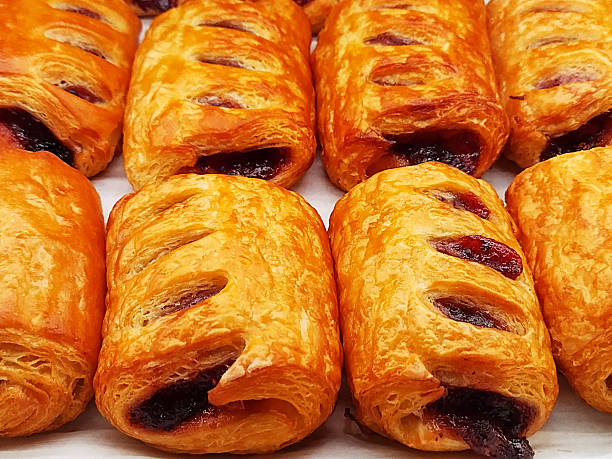 Golden-baked, individual puff pastries generously filled with a vibrant, sweet mixed berry compote, showcasing their delightful, flaky crust.