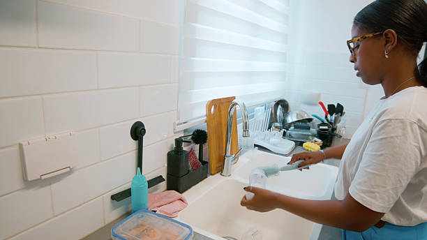 istock Young woman washing dishes in a modern kitchen 2224488396