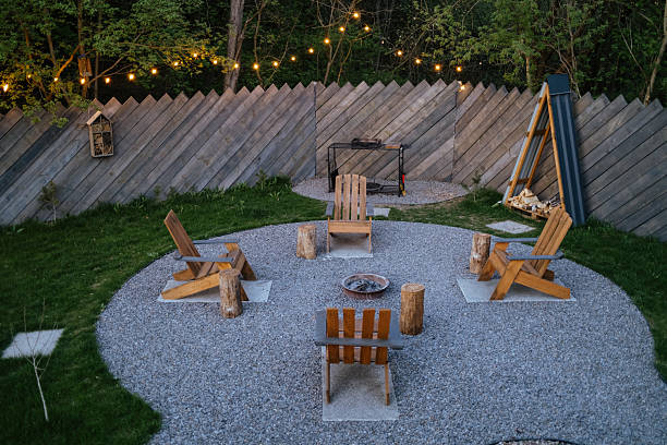 istock Cozy backyard fire pit area with wooden chairs, string lights, evening gathering 2224488418