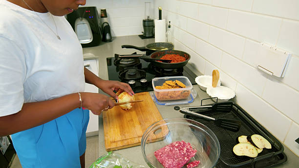 istock Woman slicing onion while preparing ingredients for cooking meal in kitchen 2224488491