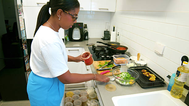istock Woman adding spices while preparing a healthy meal in a modern kitchen 2224488548