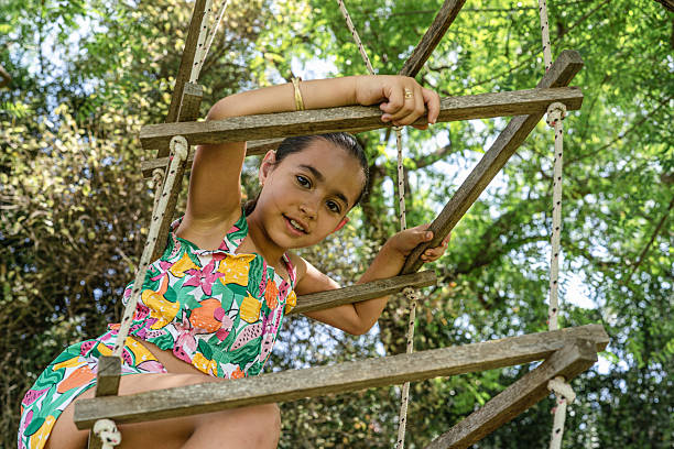 istock Child Enjoying a Sunny Day While Climbing a Rustic Wooden Rope Ladder 2224490011