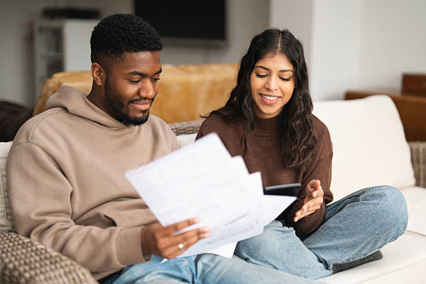 istock Couple reviewing documents together at home, sharing smiles and discussing plans for future projects in a cozy living room setting 2224491324