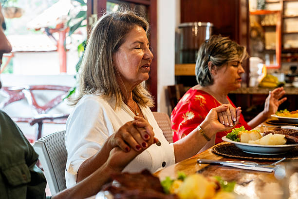 Family gathered at home, praying before lunch