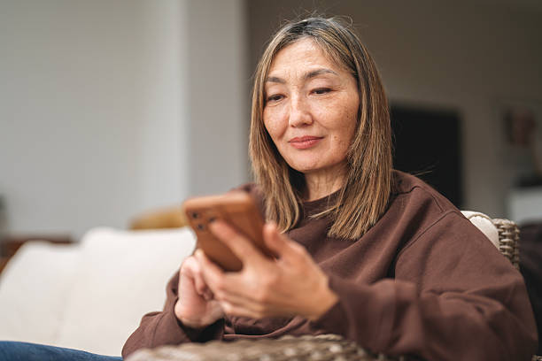 istock Woman relaxing at home while using smartphone in cozy living room setting during late afternoon 2224492968