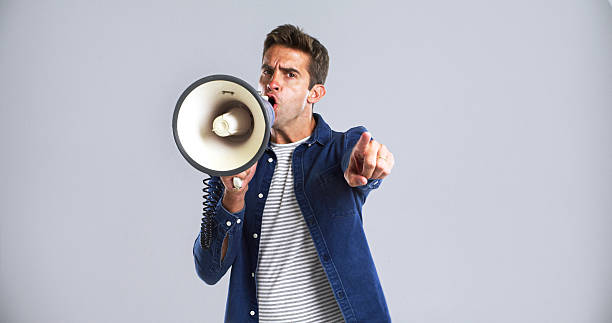 istock Portrait, bullhorn and man in studio, screaming or angry with protest on white background. Facial expression, person or point with megaphone, frustrated or activism for human rights, noise or justice 2224496593