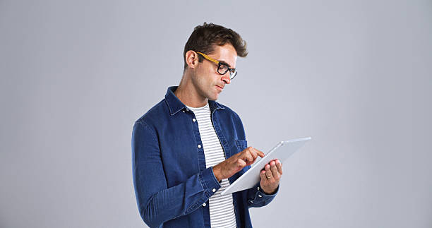 istock Glasses, journalism and tablet with editor man in studio for proofreading article of online magazine. App, editing and website post with freelance journalist on white background space for publishing 2224496620