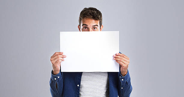 istock Man, portrait and presentation with billboard in studio for advertising on white background. Male person, model or showing with poster or sign for message, notification or marketing on mockup space 2224496625
