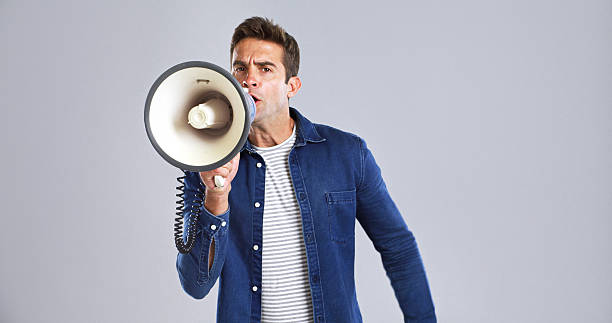 istock Portrait, bullhorn and man in studio, shouting or angry with protest on white background. Expression, person or model with megaphone, frustrated or activism for human rights, voice or social justice 2224496628