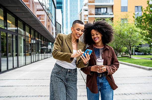 istock Two female friends using a smartphone and drinking coffee in the city 2224497324