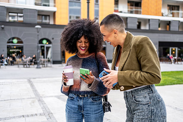 istock Two young women laughing while using smartphones in the city 2224498510