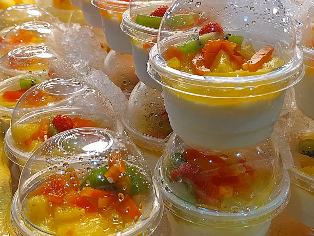 An appealing display of chilled soy pudding cups, each generously garnished with a vibrant mix of local fruits, a delightful sweet treat found in Thailand.