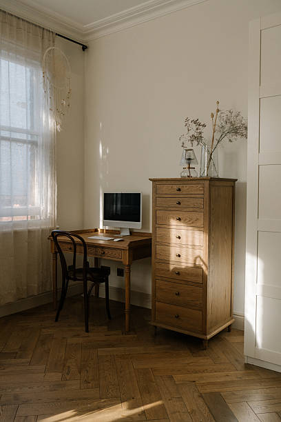 istock Minimalistic workspace with computer and keyboard, illuminated by natural light. Wooden desk, linen curtains, wooden chest of drawers, vintage style room interior 2224498842