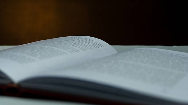 istock Open book with blurred text under warm light against black background, moody still life concept evoking mystery, memory, and quiet contemplation 2224499946