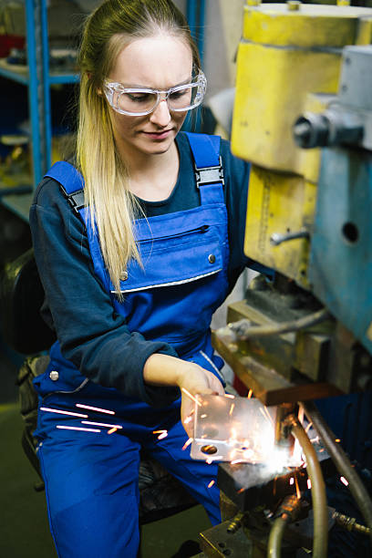 istock Young female trainee welds steel with grinder in workshop 2224500072