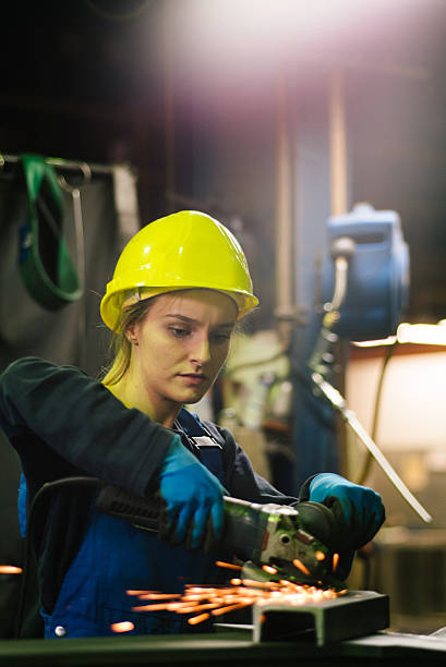 istock Young female trainee welds steel with grinder in workshop 2224500155