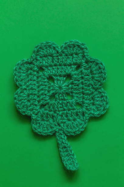 istock Green crochet shamrock or clover leaf cup coaster on a green background. Top view. St. Patrick day concept. 2224506002