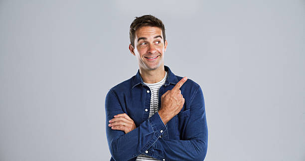 istock Pointing, thinking and man in studio, promotion and announcement on gray background. Solution, mockup space and model with hand gesture, smile and discount deal with sales, decision and opportunity 2224508049