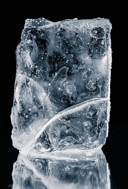 istock Textured natural ice block with cracks, on a black background with reflection. A melting piece of ice. 2224508233