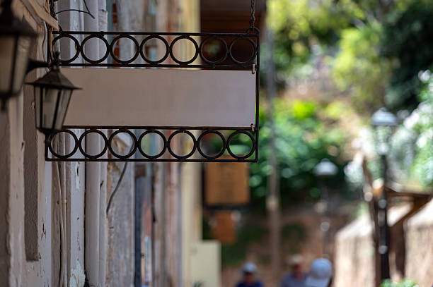 istock Blank signboard mockup in a quaint street surrounded by greenery 2224509903