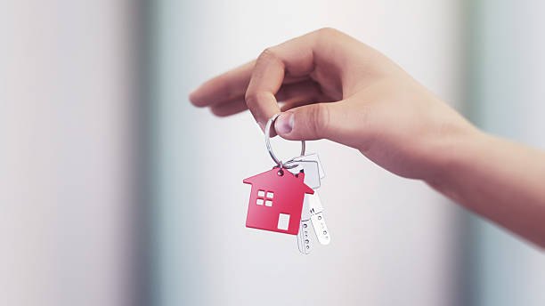 istock Metallic House Keys on Red Plastic House Shaped Keychain in Human Hand on Soft Background 2224510743
