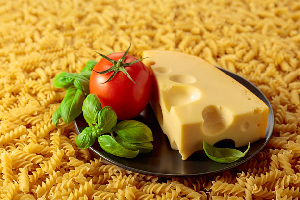 Uncooked fusilli pasta with tomato, basil and cheese. Italian cuisine.